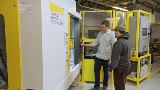 Instructor talking to student while standing next to a FANUC ROBODRILL machine